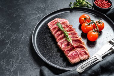 Tabakta dilimlenmiş Top Blade bifteği. Organik et. Siyah arka plan. Üst Manzara. Boşluğu kopyala.