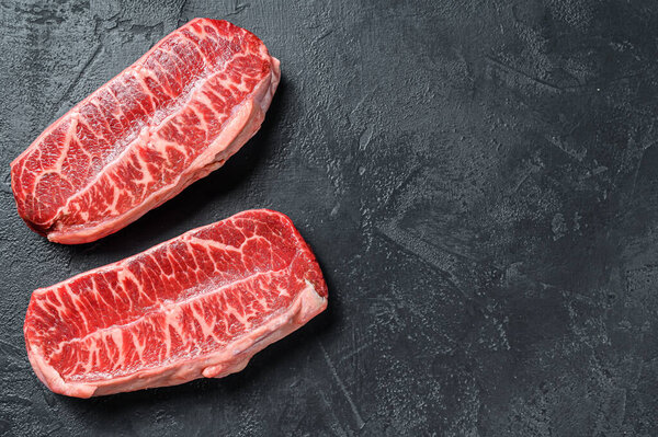 Raw organic meat Twagyu oyster top blade steak. Black background. Top view. Copy space.