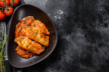 Fırında Tilapia balığı ve domates tabağı. Siyah arka plan. Üst Manzara. Boşluğu kopyala.