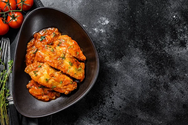 Fırında Tilapia balığı ve domates tabağı. Siyah arka plan. Üst Manzara. Boşluğu kopyala.