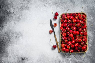 Tahta bir kasede kirazlar. Taze kirazlar. Gri arka plan. Üst Manzara. Boşluğu kopyala.