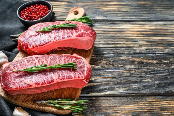 Raw marbled beef steak, top blade meat steak. Black background. Top view. Copy space