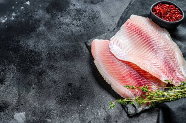 Kekik ve pembe biberli çiğ tilapia fileto. Siyah arka plan. Üst Manzara. Boşluğu kopyala.