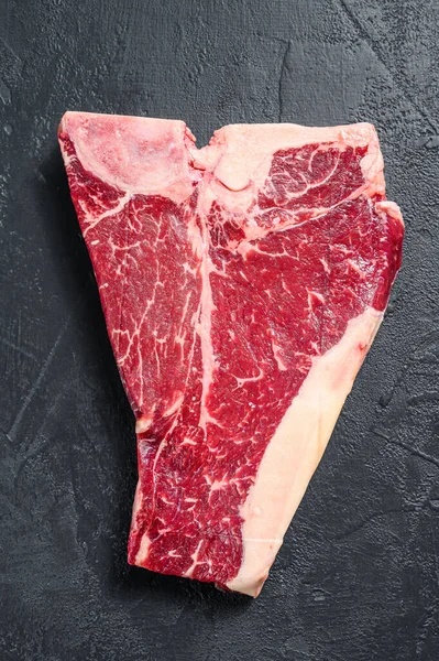 Kalın Raw T-Bone bifteği. Siyah arka plan. Üst görünüm.