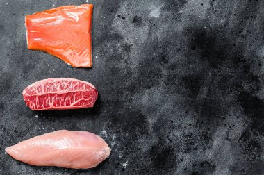 Farklı türde çiğ et. Biftek bıçağı, somon filetosu ve hindi göğsü. Siyah arka plan. Üst Manzara. Boşluğu kopyala.