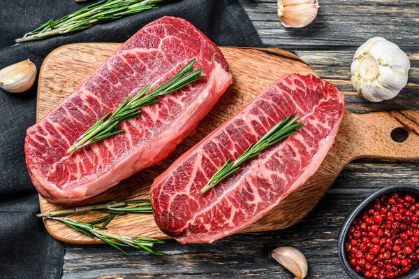 Raw organic meat Twagyu oyster top blade steak. Black wooden background. Top view.