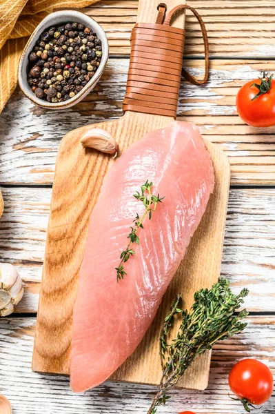 Çiğ hindi bifteği. Otlu göğüs filetosu. Beyaz ahşap arka plan. Üst görünüm.