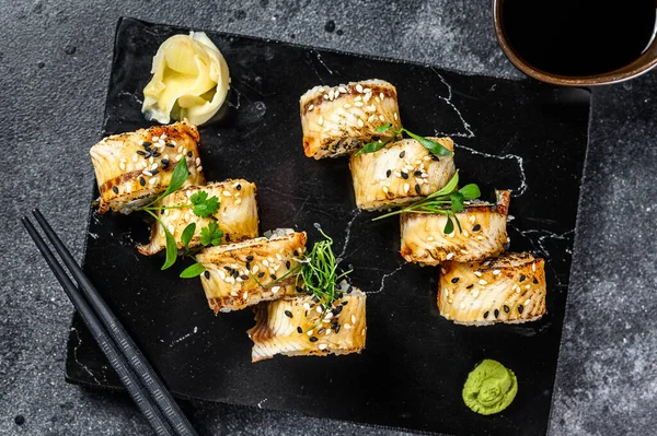 Suşi, Maki suşisi, füme yılan balığı ve salatalık. Siyah arka plan. Üst görünüm.