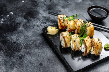 Füme yılan balığı ve salatalıklı suşi rulosu. Siyah arka plan. Üst Manzara. Boşluğu kopyala.