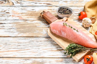 Çiğ hindi bifteği. Otlu göğüs filetosu. Beyaz ahşap arka plan. Üst Manzara. Boşluğu kopyala.