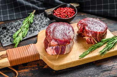 Kesme tahtasının üzerinde çiğ biftek fileto fileto. Karanlık ahşap arka plan. Üst görünüm.