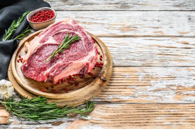 Çiğ kovboy bifteği ya da kemik üzerinde pirzola. Mermer biftek. Beyaz ahşap arka plan. Üst Manzara. Boşluğu kopyala.