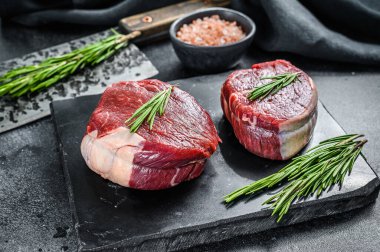 Filetodan kesilmiş iki parça ince biftek. Siyah arka plan. Üst görünüm