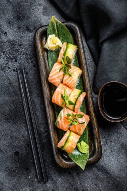 Somon, avokado ve krem peynirli Philadelphia suşisi. Suşi menüsü. Japon yemeği. Siyah arka plan. Üst görünüm.