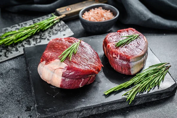 Filetodan kesilmiş iki parça ince biftek. Siyah arka plan. Üst görünüm