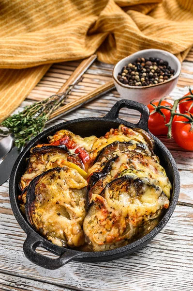 Dökme demir tabakta pişirilmiş sebzeli ratatouille. Ahşap arka plan. Üst görünüm.