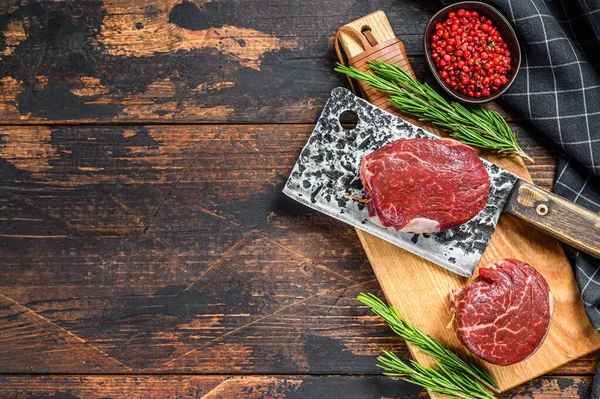 Kesme tahtasında çiğ mermer et fileto mignon. Karanlık ahşap arka plan. Üst Manzara. Boşluğu kopyala.