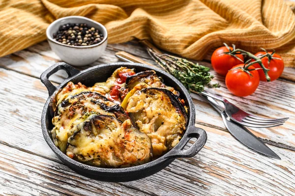 Dökme demir tabakta pişirilmiş sebzeli ratatouille. Ahşap arka plan. Üst görünüm.