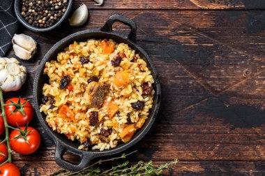 Tavada kuzu eti ve sebzeli pilav. Koyu ahşap arka plan. Üst Manzara. Boşluğu kopyala.