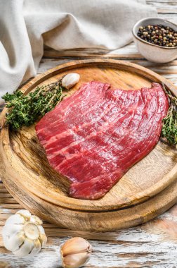 Kesme tahtasında çiğ çiğ demir biftek. Taze mermer et, siyah Angus. Beyaz ahşap arka plan. Üst görünüm.