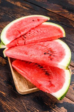 Bir yığın taze kırmızı dilimlenmiş karpuz. Karanlık ahşap arka plan. Üst görünüm.