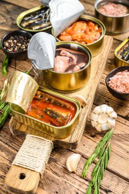 Açılmış kutular saury, somon, sprat, sardalya, kalamar ve ton balığıyla korunur. Ahşap arka plan. Üst görünüm.