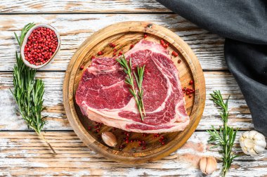 Çiğ kovboy bifteği ya da kemik üzerinde pirzola. Mermer biftek. Beyaz ahşap arka plan. Üst görünüm