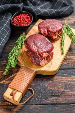 Kesme tahtasında çiğ mermer et fileto mignon. Karanlık ahşap arka plan. Üst görünüm.