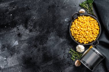 Tavada tatlı konserve mısır taneleri. Siyah arka plan. Üst Manzara. Boşluğu kopyala.