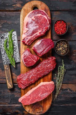 Çiğ siyah angus bifteği fileto Mignon, pirzola ya da kovboy, Striploin ya da New York, etek ya da pala. Ahşap arka plan. Üst görünüm.