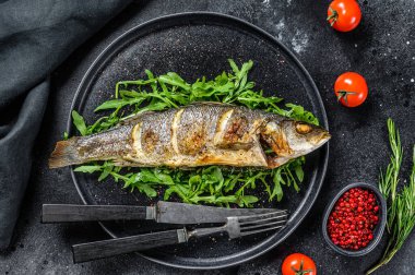 BBQ deniz levreği, roka ve kızarmış levrek. Siyah arka plan. Üst görünüm.