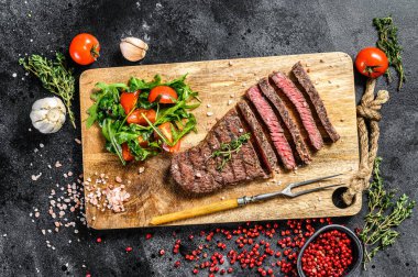 Kesme tahtasında ızgara Denver bifteği. Barbekü bifteği. Siyah arka plan. Üst görünüm.