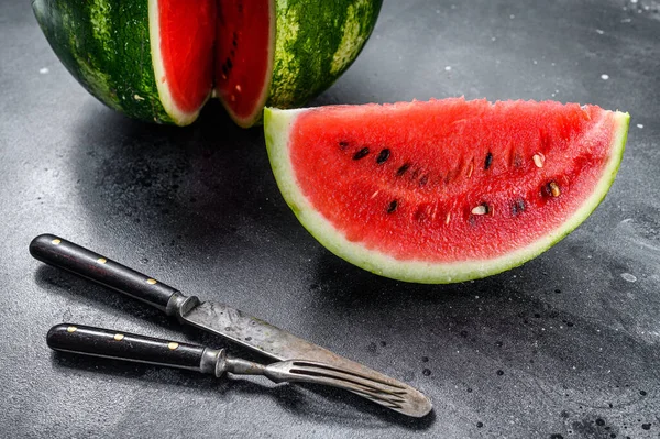 Red ripe watermelon with cut-out slices. Black background. Top view.
