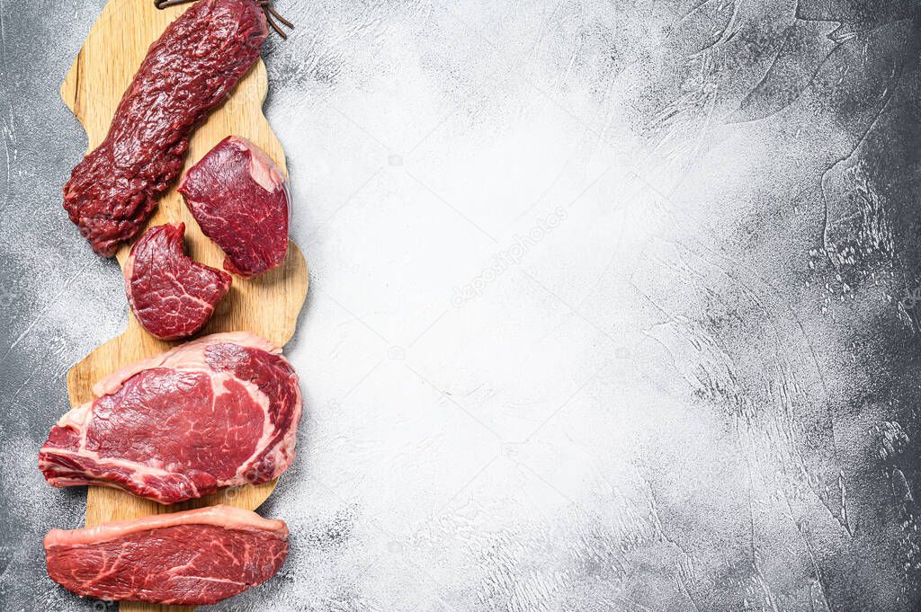 Variety of raw black angus beef meat steaks fillet Mignon, rib eye or cowboy, Striploin or new york, skirt or machete. White background. Top view. Copy space.