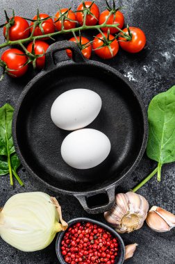 Shakshuka pişirmek için gerekli malzemeler. Yumurta, soğan, sarımsak, domates, biber, ıspanak. Siyah arka plan. Üst görünüm.