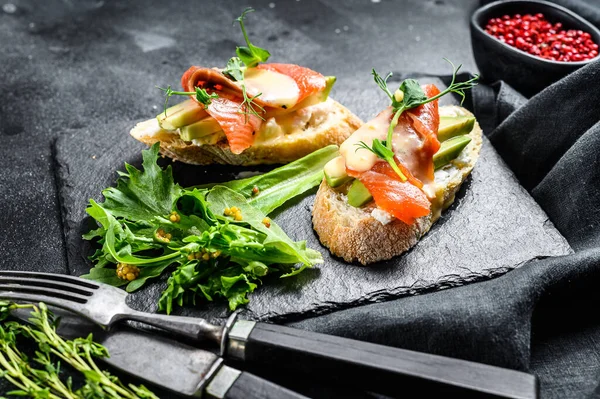 Avokado ve somonlu sağlıklı sandviç. Ispanak ve roka salatası. Siyah arka plan. Üst görünüm.