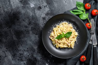 İtalyan usulü makarna. Krema soslu, pastırmalı ve fesleğenli tarif. Hazır risoni. Siyah ahşap arka plan. Üst Manzara. Boşluğu kopyala.