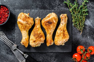 Baharatlı tavuk budu, baharatlı bacaklar ve otlar. Siyah arka plan. Üst görünüm.