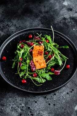 Alabalık, roka, marul ve kızılcıklı deniz ürünleri salatası. Siyah arka plan. Üst görünüm.