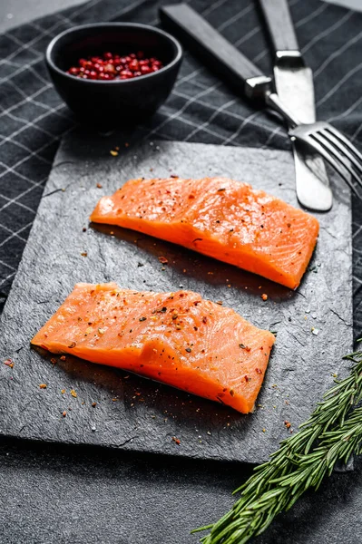 Taş bir tahtanın üzerinde fileto somon bifteği. Siyah arka plan. Üst görünüm.