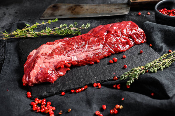 Raw strip vegas beef steak with pink pepper and thyme. Black background. Top view.