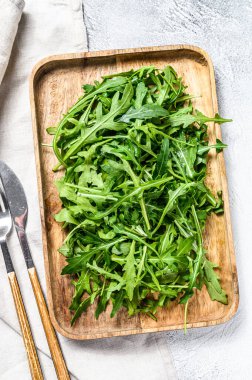 Tahta kasede taze roka salatası. Gri arka plan. Üst görünüm.