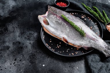 Kafasız, tuzsuz ve biberiyeli çiğ alabalık. Siyah arka plan. Üst Manzara. Boşluğu kopyala.