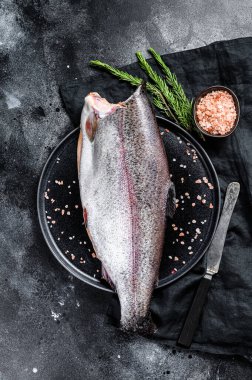 Kafasız, tuzsuz ve biberiyeli çiğ alabalık. Siyah arka plan. Üst görünüm.