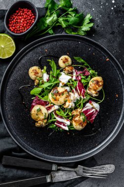 Kızarmış mürekkep balığı ve roka salatası. Siyah arka plan. Üst görünüm.