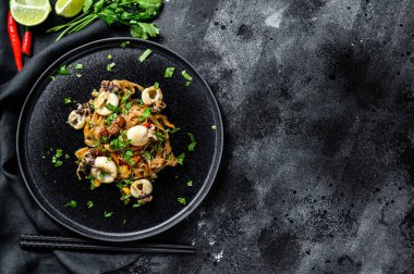 Asya usulü kalamar ve sebzeli erişte kızartması. Siyah arka plan. Üst Manzara. Boşluğu kopyala.