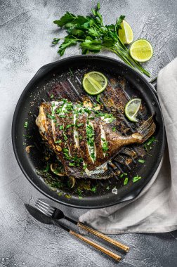 Limonlu kızarmış Dory balığı ve tavada maydanoz. Vejetaryen sağlıklı yiyecekler. Gri arka plan. Üst görünüm.