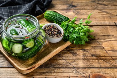 Cam kavanozda yeşil salatalık. Ahşap arka plan. Üst Manzara. Boşluğu kopyala.