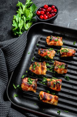 Domuz pastırmasına sarılmış kızarmış tavuk göğsü. Siyah arka plan. Üst görünüm