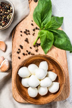 Tahta bir kasede fesleğen yapraklı Mozzarella peyniri. gri arka plan. Üst görünüm.